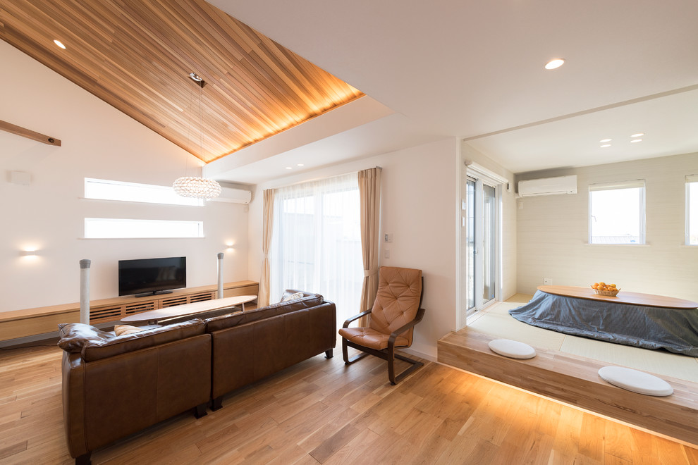 Modelo de salón nórdico con paredes blancas, suelo de madera clara y televisor independiente