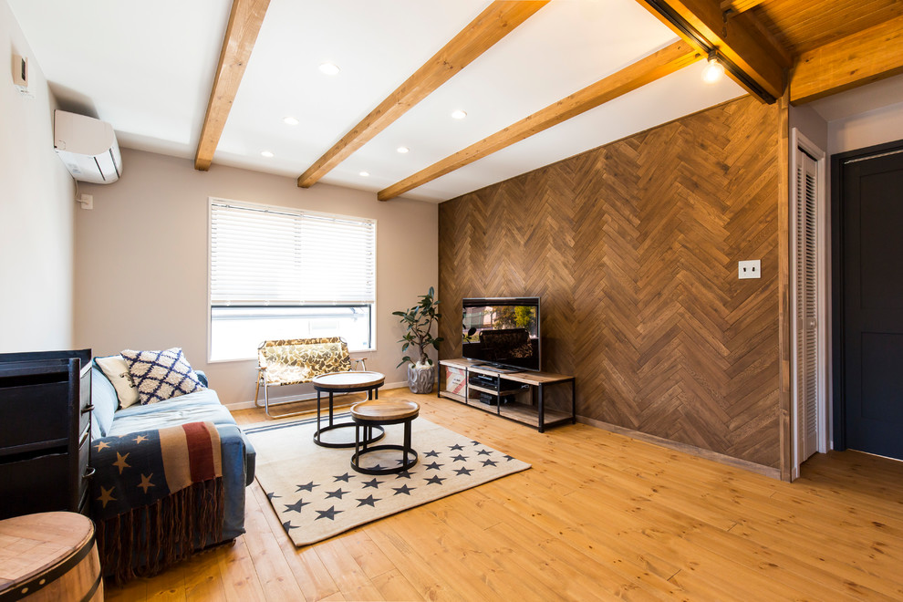 Cette photo montre un salon industriel avec un sol en bois brun, un mur multicolore, un téléviseur indépendant et un sol marron.