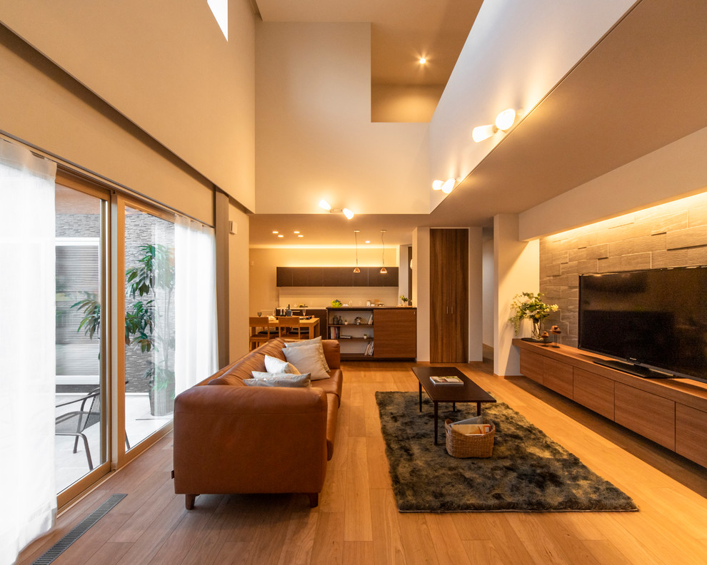 Imagen de salón abierto minimalista grande con paredes blancas, suelo de madera en tonos medios, televisor independiente y suelo marrón