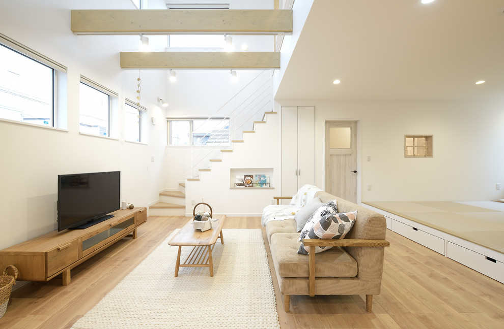 Nordisches Wohnzimmer mit weißer Wandfarbe, gebeiztem Holzboden, freistehendem TV und beigem Boden in Sapporo