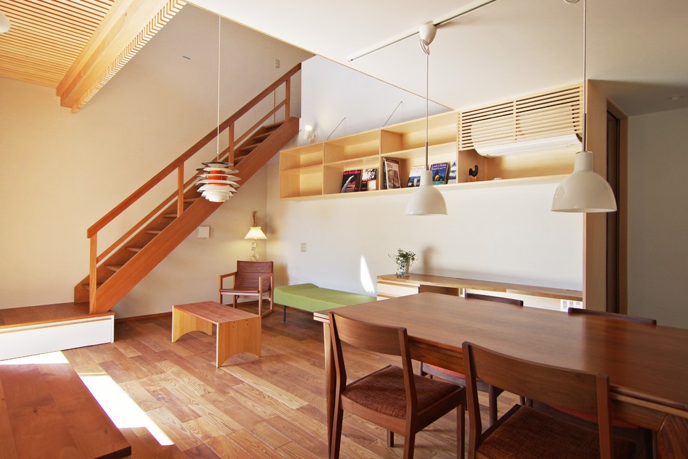 Offenes Modernes Wohnzimmer ohne Kamin mit weißer Wandfarbe, braunem Holzboden und freistehendem TV in Sonstige