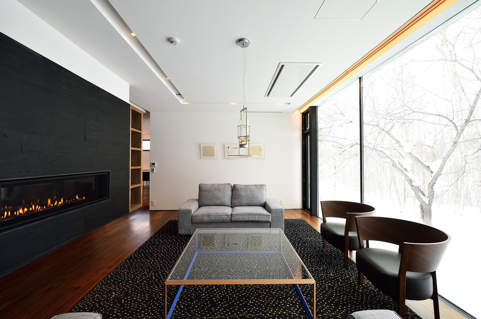 Abgetrenntes Modernes Wohnzimmer mit weißer Wandfarbe, braunem Holzboden und Gaskamin in Sapporo