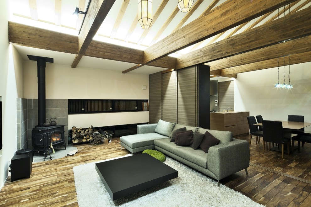 Идея дизайна: гостиная комната в современном стиле с белыми стенами, паркетным полом среднего тона, печью-буржуйкой, фасадом камина из бетона и коричневым полом