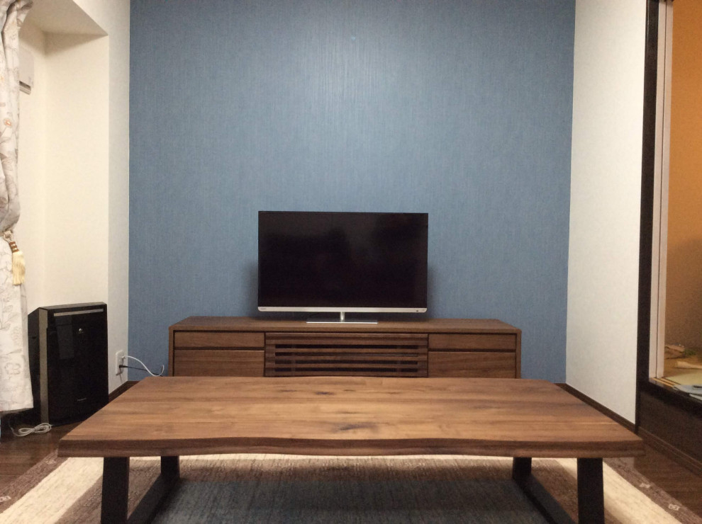Imagen de biblioteca en casa abierta moderna de tamaño medio con paredes azules, suelo de contrachapado, televisor independiente, suelo marrón, papel pintado y papel pintado
