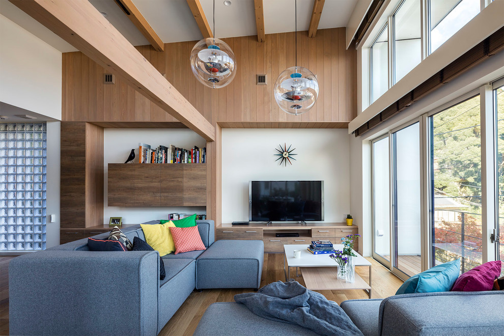 Modernes Wohnzimmer mit bunten Wänden, hellem Holzboden, Multimediawand und beigem Boden in Sonstige