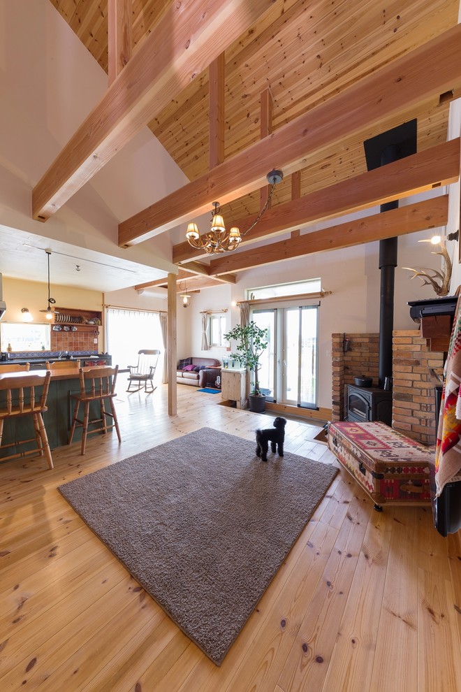Exemple d'un salon nature ouvert avec un mur blanc, un sol en bois brun, une cheminée d'angle, un manteau de cheminée en brique et un sol marron.
