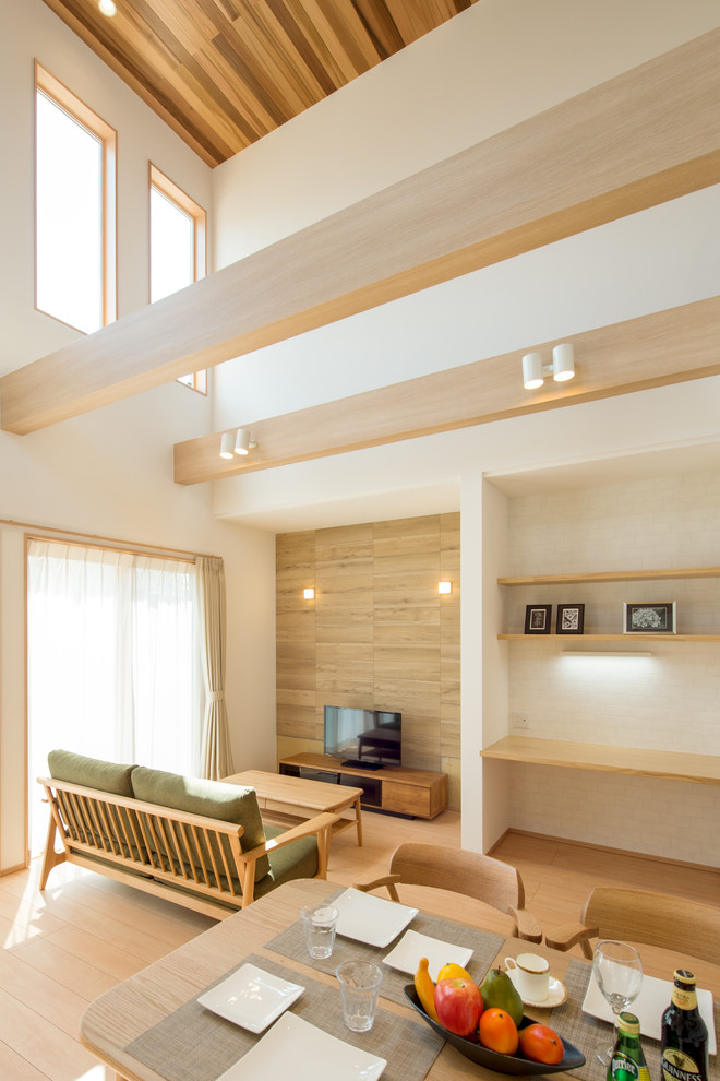 Imagen de salón abierto nórdico con paredes blancas, suelo de madera clara, televisor independiente y suelo beige