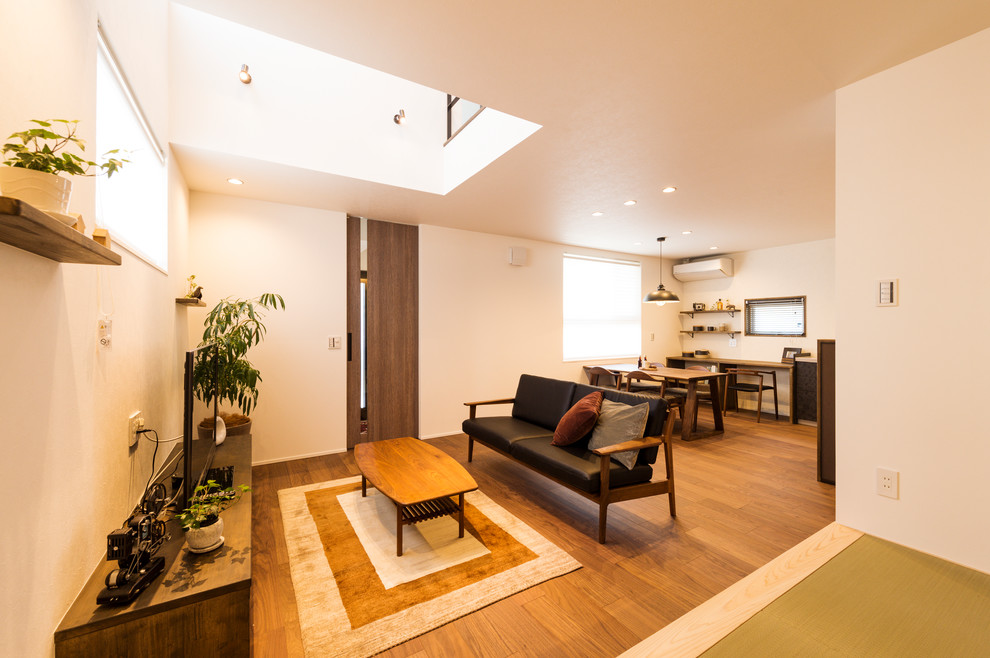 Idee per un soggiorno etnico aperto con pareti bianche, pavimento in legno massello medio, TV autoportante e pavimento marrone