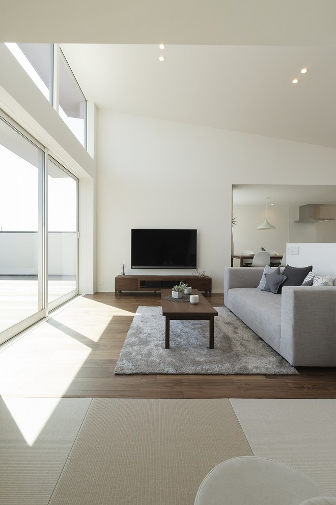 Foto de salón abierto minimalista sin chimenea con paredes blancas, suelo de madera oscura, televisor colgado en la pared y suelo marrón