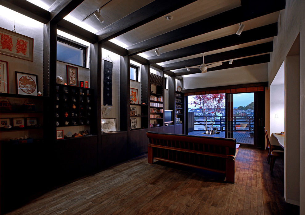 Esempio di un soggiorno etnico aperto con libreria, parquet scuro, nessun camino, TV autoportante e pavimento marrone