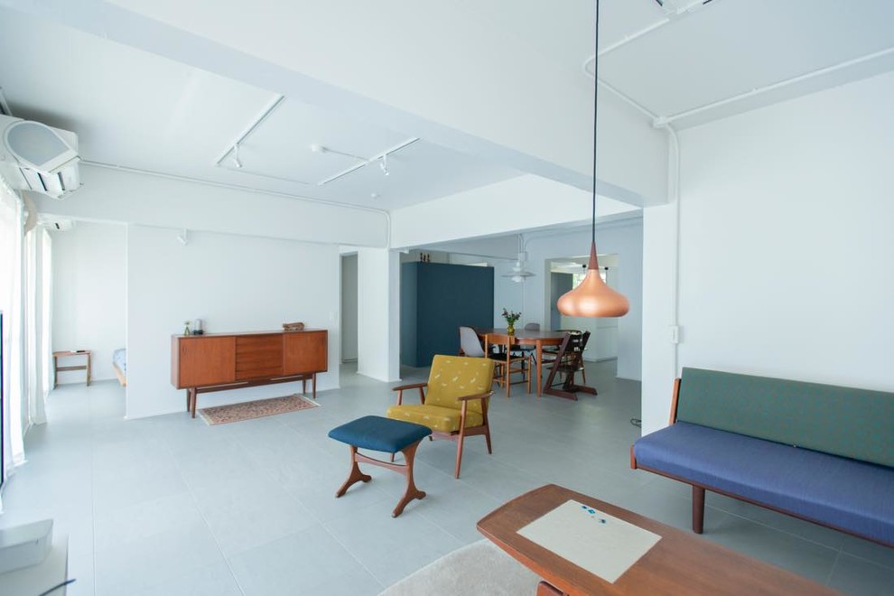 This is an example of an industrial open plan living room in Tokyo with white walls and grey floors.