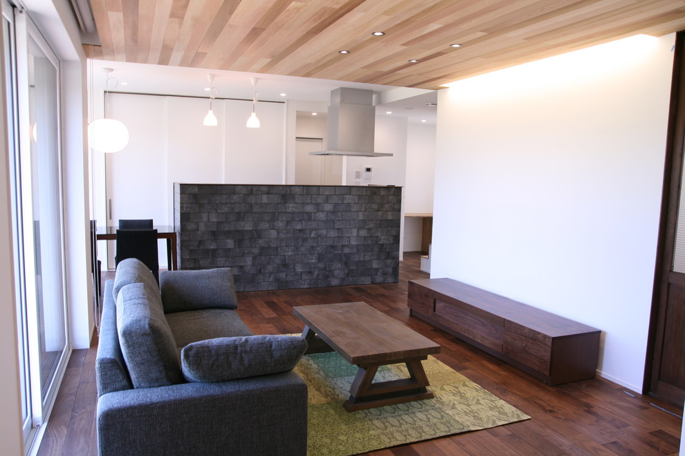 Foto på ett funkis vardagsrum, med vita väggar, mörkt trägolv och brunt golv