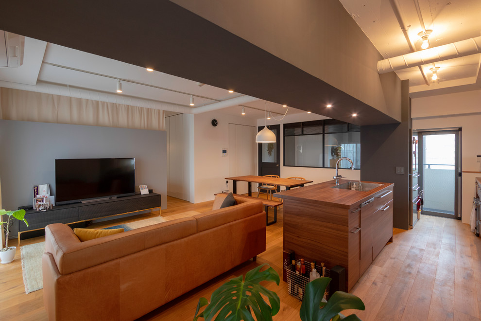Cette photo montre un salon tendance avec un mur blanc, un sol en bois brun, un téléviseur indépendant et un sol marron.