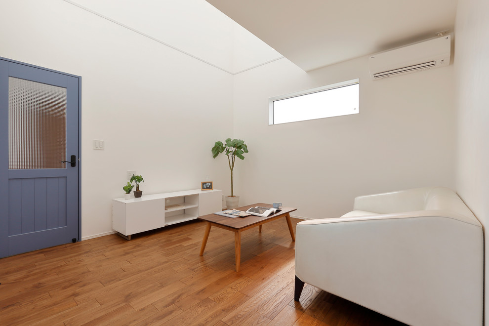 На фото: открытая гостиная комната в скандинавском стиле с белыми стенами, паркетным полом среднего тона, отдельно стоящим телевизором и коричневым полом с