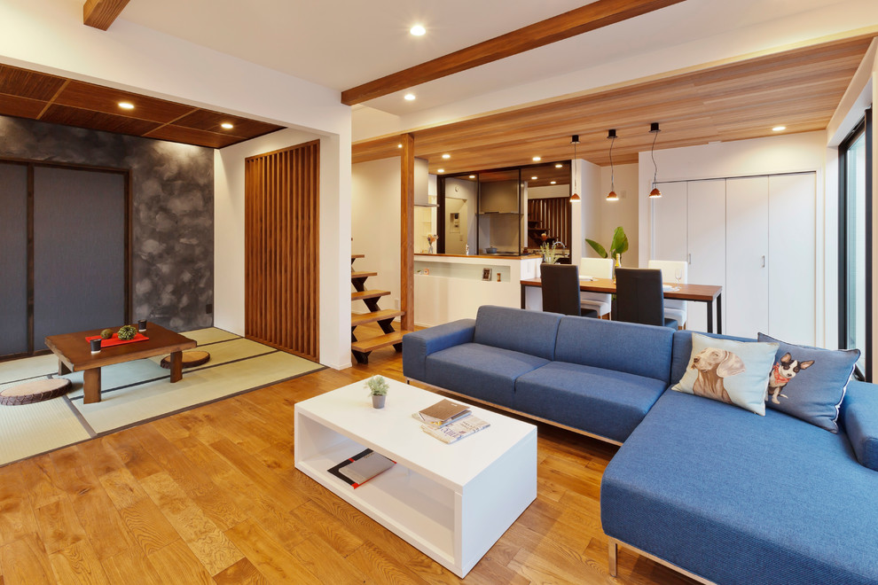 Aménagement d'un salon asiatique avec un mur blanc, un sol en bois brun et un sol marron.