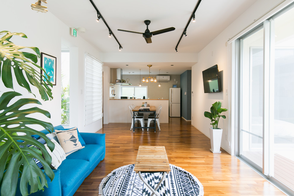 Offenes Maritimes Wohnzimmer mit weißer Wandfarbe, braunem Holzboden, TV-Wand und braunem Boden in Sonstige