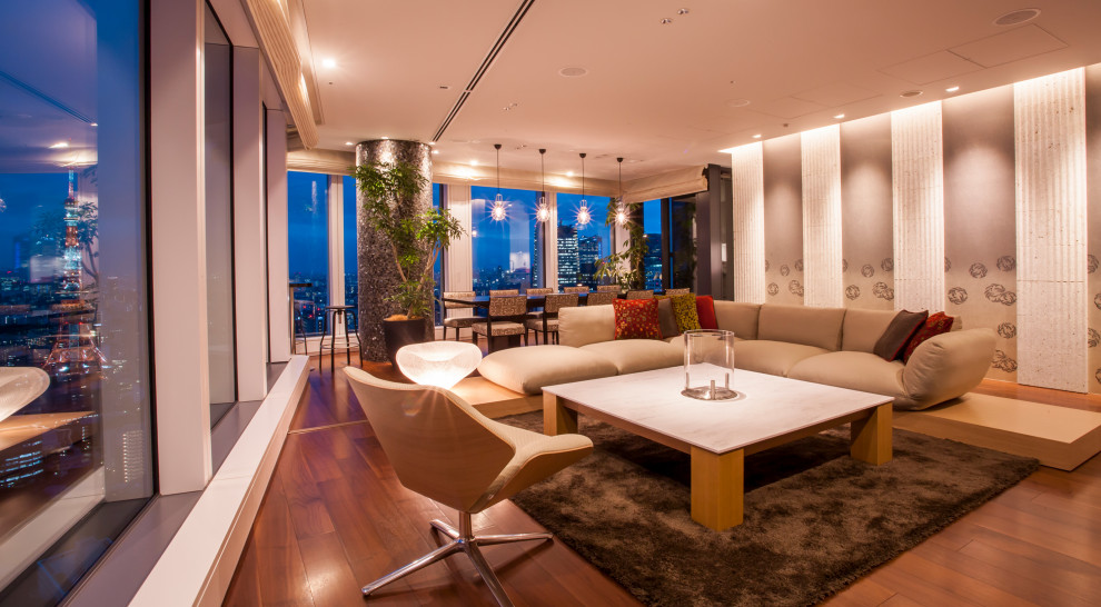 Modelo de salón minimalista grande con paredes grises, televisor colgado en la pared y suelo marrón