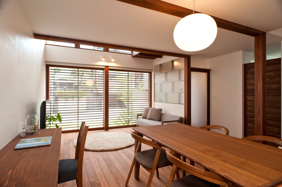 Diseño de salón abierto de estilo zen con paredes blancas, suelo de madera en tonos medios, televisor independiente y suelo marrón