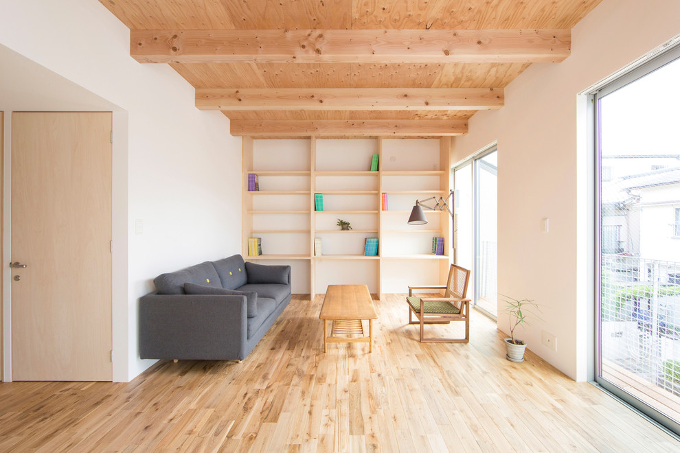 Immagine di un soggiorno etnico aperto con libreria, pareti bianche, parquet chiaro e pavimento marrone