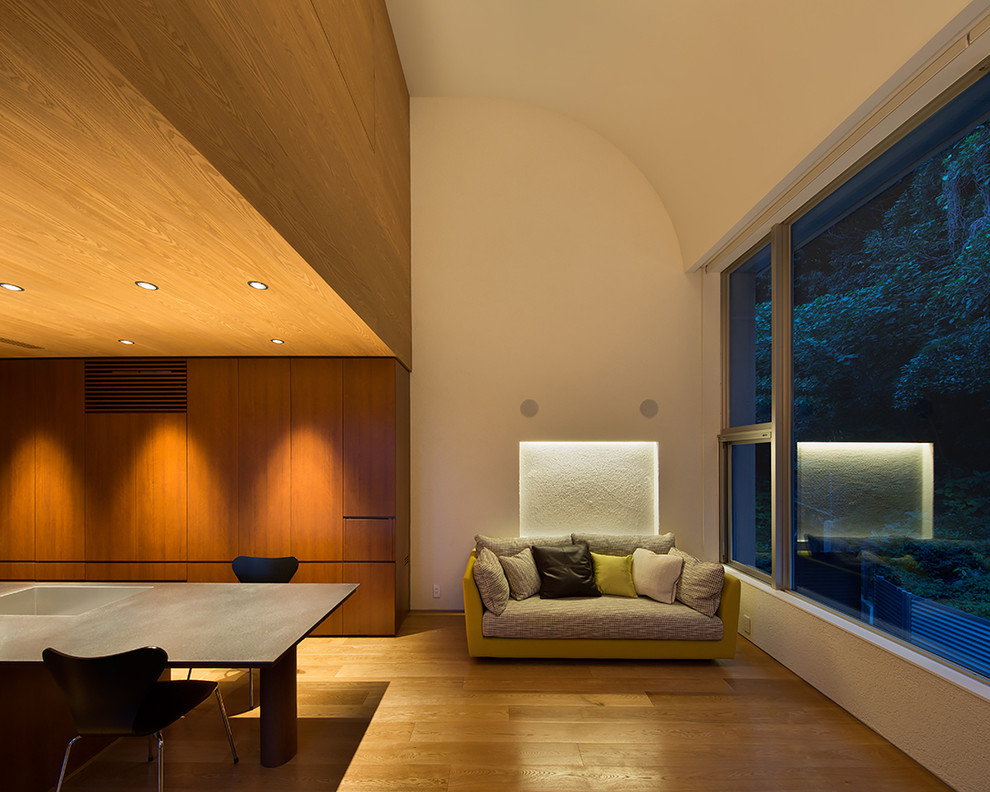 Esempio di un soggiorno minimalista aperto con pareti bianche, pavimento in compensato e TV a parete
