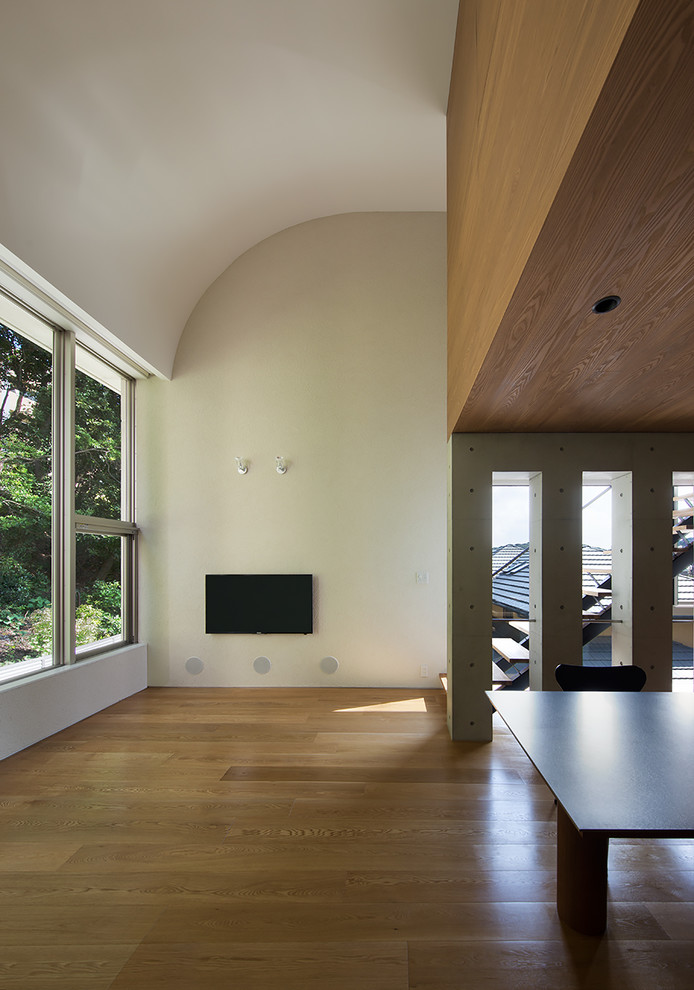 Inredning av ett modernt allrum med öppen planlösning, med vita väggar, plywoodgolv och en väggmonterad TV