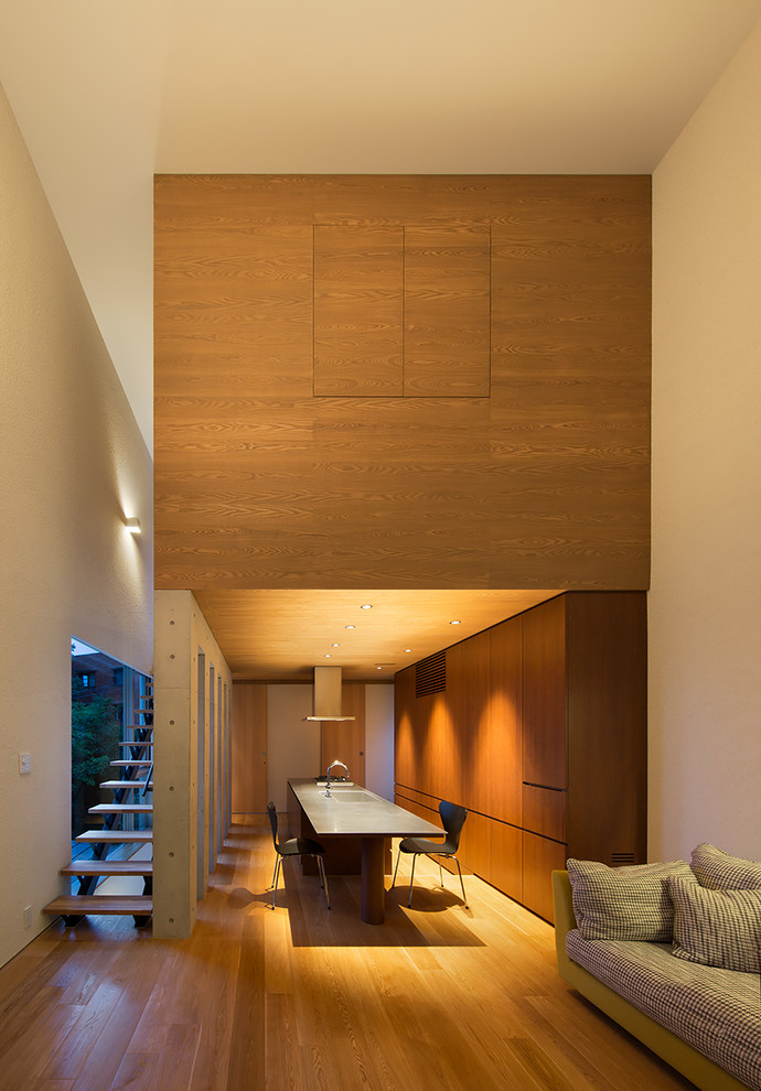 Идея дизайна: открытая гостиная комната в стиле модернизм с белыми стенами, полом из фанеры и телевизором на стене