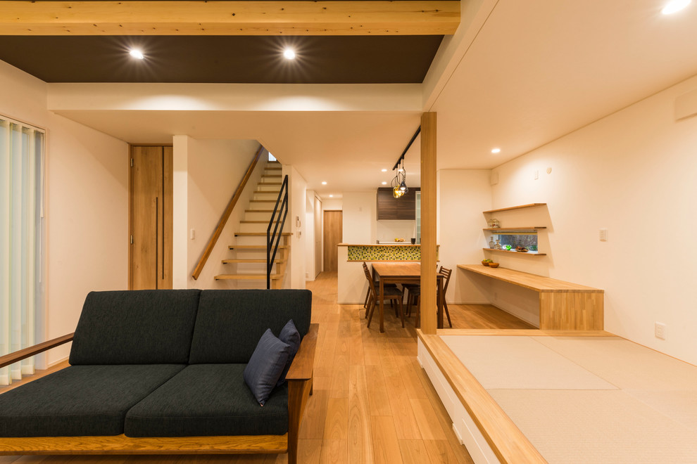 Esempio di un soggiorno minimalista di medie dimensioni e aperto con pareti bianche, pavimento in compensato, nessun camino, TV autoportante e pavimento marrone