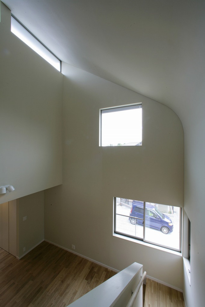Cette image montre un salon minimaliste de taille moyenne et ouvert avec une salle de réception, un mur blanc, un sol en bois brun et un téléviseur indépendant.