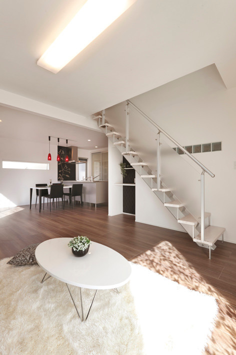 Modelo de salón abierto minimalista de tamaño medio con paredes blancas, suelo de contrachapado, televisor independiente y suelo beige