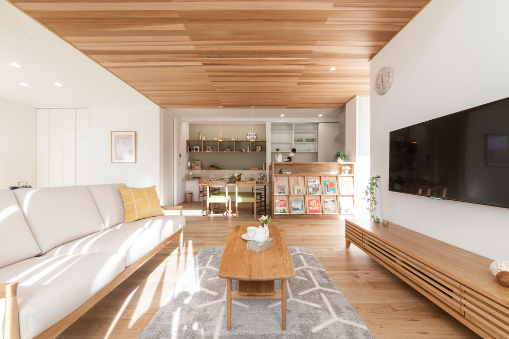 Foto di un soggiorno nordico aperto con pareti bianche, pavimento in legno massello medio, TV a parete e pavimento marrone