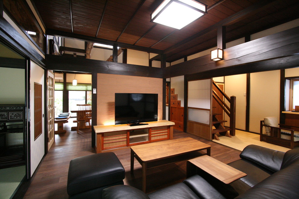 Immagine di un soggiorno etnico chiuso con pareti beige, parquet scuro, TV autoportante e pavimento marrone