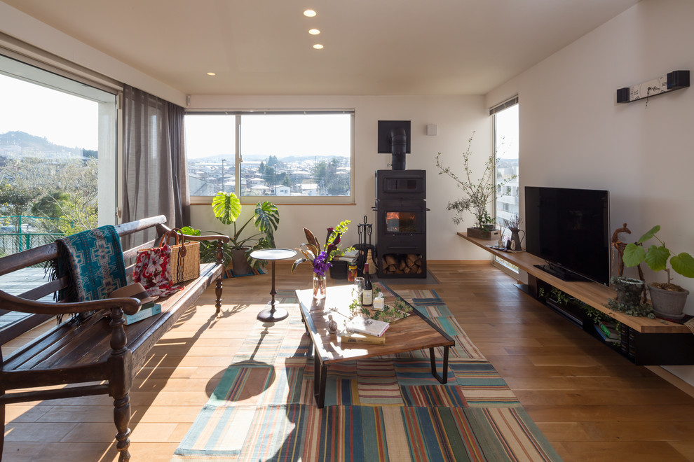 Bild på ett eklektiskt separat vardagsrum, med vita väggar, mellanmörkt trägolv, en öppen vedspis, en fristående TV och brunt golv