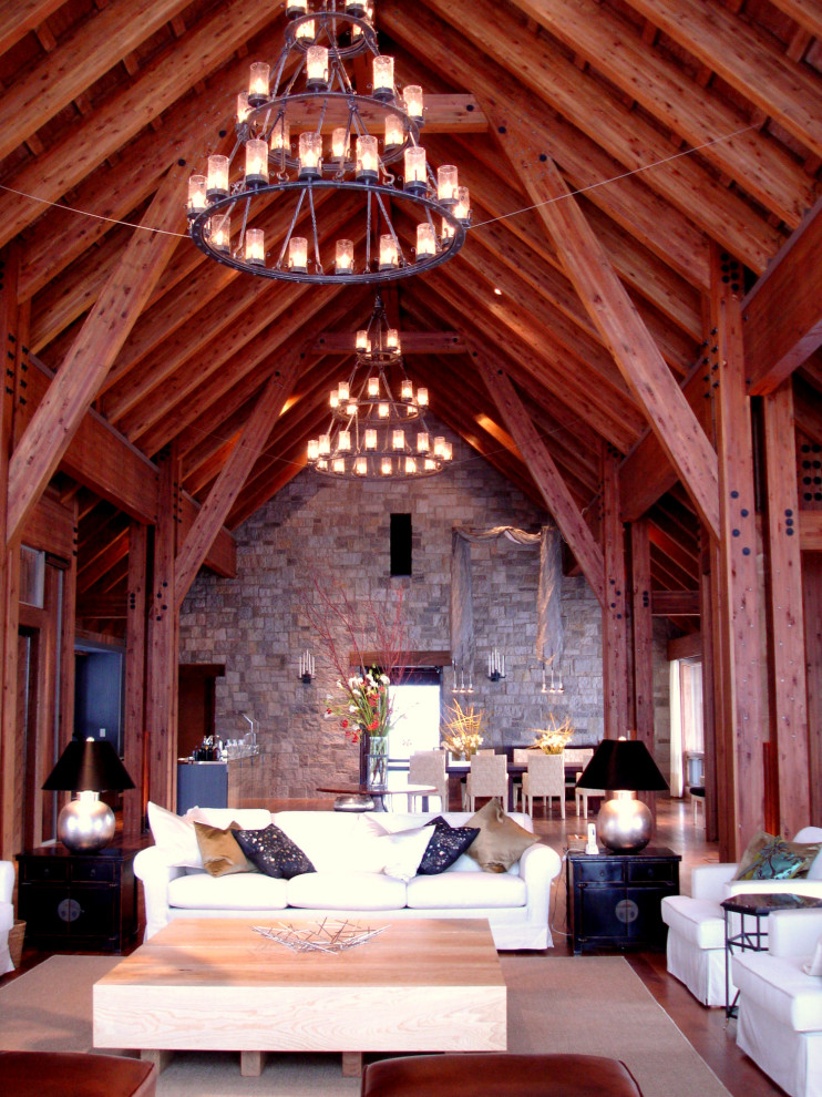 Cette photo montre un grand salon chic ouvert avec une salle de réception, un mur marron, un sol en contreplaqué, une cheminée standard, un manteau de cheminée en pierre, un téléviseur indépendant et un sol marron.