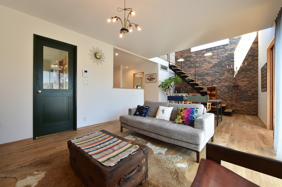 На фото: гостиная комната в стиле лофт с белыми стенами, светлым паркетным полом и коричневым полом