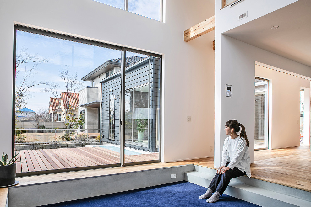 Источник вдохновения для домашнего уюта: открытая гостиная комната в современном стиле с светлым паркетным полом, телевизором на стене, синим полом и потолком с обоями без камина