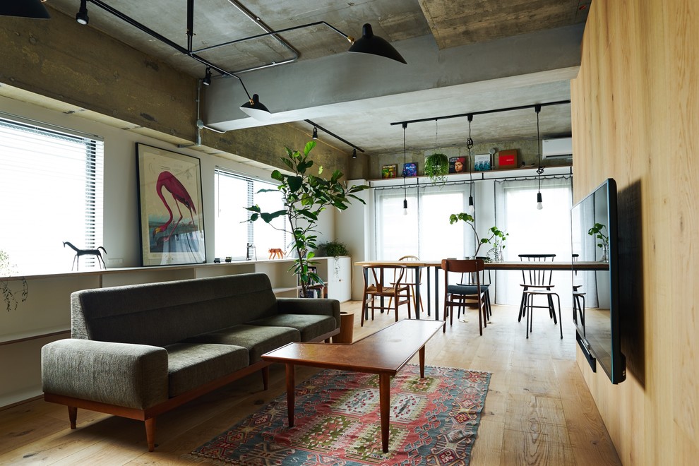Immagine di un soggiorno industriale con pareti multicolore, pavimento in legno massello medio, TV a parete e pavimento marrone