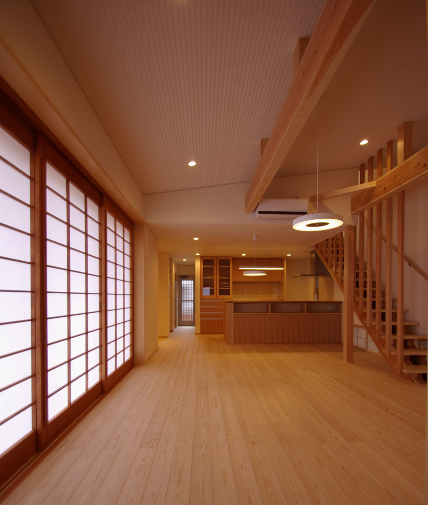 Inredning av ett asiatiskt litet allrum med öppen planlösning, med ett finrum, beige väggar, ljust trägolv, en spiselkrans i trä, en inbyggd mediavägg och beiget golv