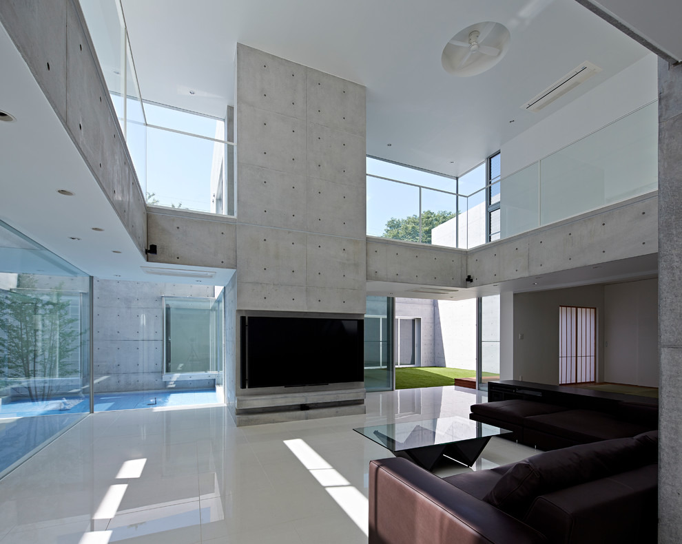 Idée de décoration pour un salon minimaliste avec un mur gris, un sol en carrelage de céramique, aucune cheminée et un téléviseur fixé au mur.