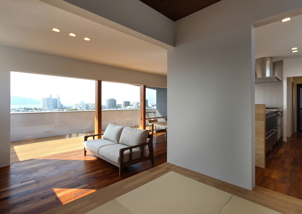 Modelo de salón abierto y blanco minimalista grande con paredes blancas, suelo de madera oscura, televisor independiente, papel pintado y papel pintado