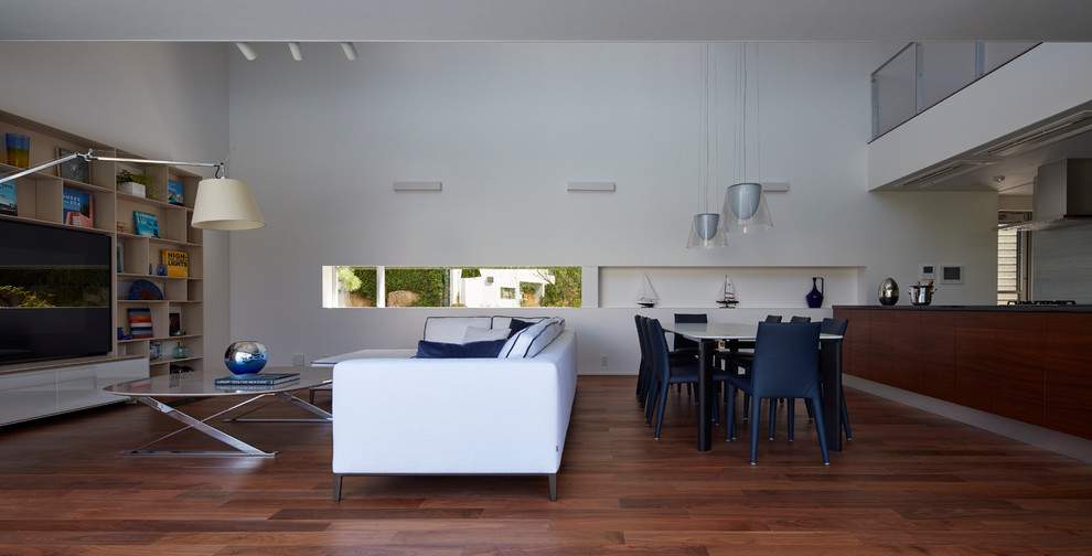 Imagen de salón para visitas abierto contemporáneo grande sin chimenea con paredes blancas, suelo de madera en tonos medios y pared multimedia