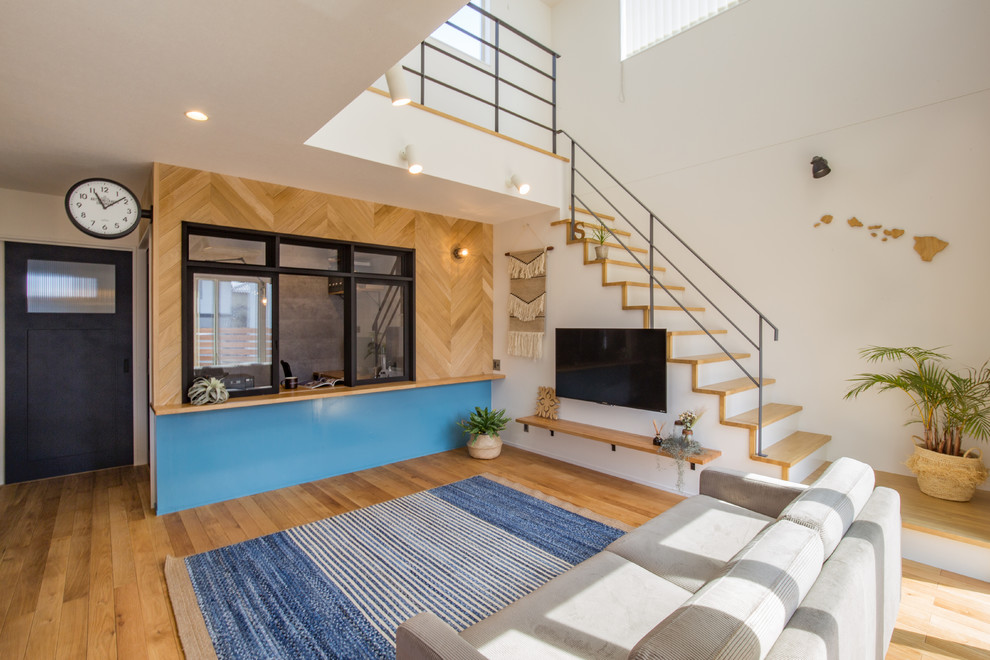 Maritimes Wohnzimmer mit weißer Wandfarbe, braunem Holzboden, TV-Wand und braunem Boden in Sonstige