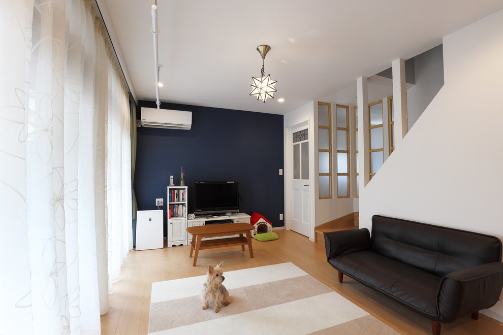 Foto på ett mellanstort funkis allrum med öppen planlösning, med vita väggar, plywoodgolv, en fristående TV och beiget golv