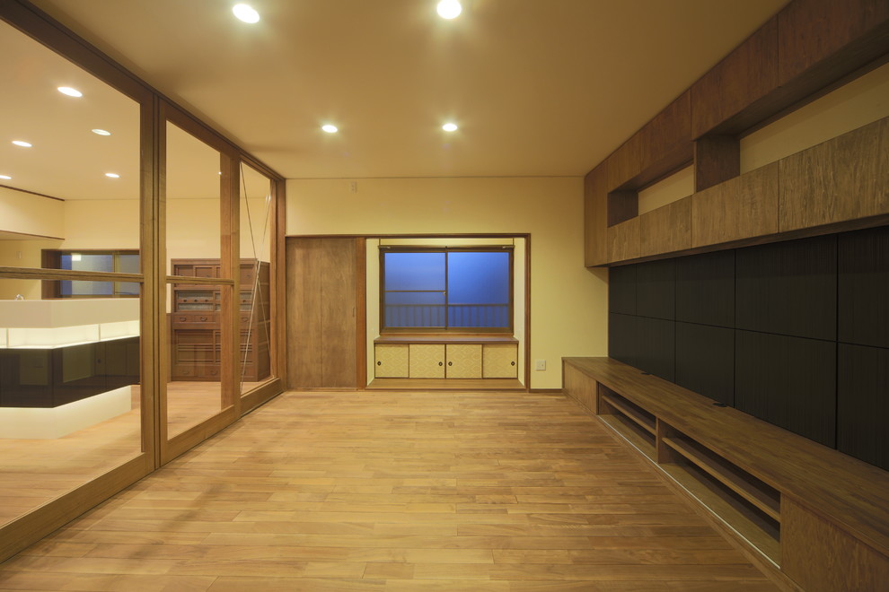 Modelo de salón con rincón musical cerrado asiático grande con paredes blancas, suelo de madera en tonos medios y televisor independiente