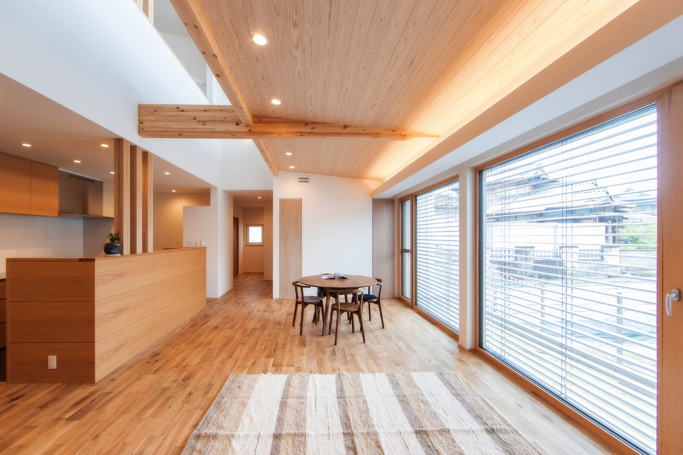Großes, Offenes Asiatisches Wohnzimmer ohne Kamin mit weißer Wandfarbe, braunem Holzboden und TV-Wand in Sonstige