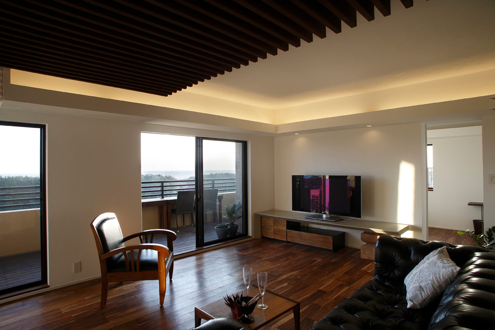 Foto på ett orientaliskt vardagsrum, med vita väggar, mellanmörkt trägolv, en fristående TV och brunt golv