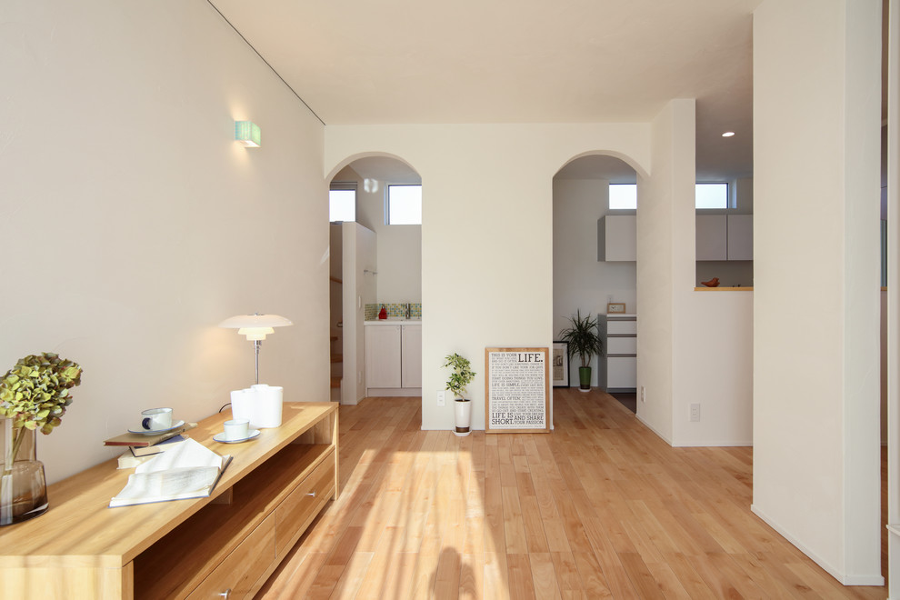 Modelo de salón abierto campestre de tamaño medio con paredes blancas y suelo de madera en tonos medios