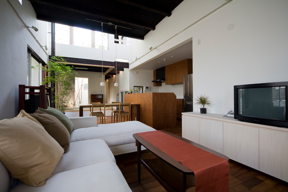 Idee per un soggiorno etnico aperto con pareti bianche, parquet scuro, TV autoportante e pavimento marrone