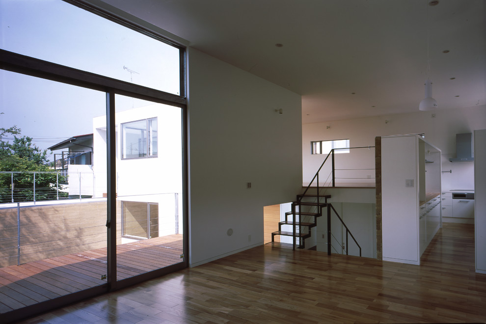 Réalisation d'un grand salon minimaliste ouvert avec un mur beige, un sol en bois brun, un téléviseur indépendant et un sol beige.