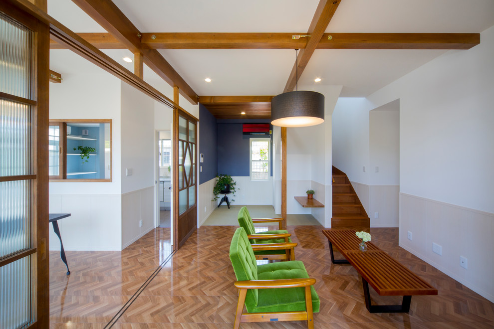 Offenes Nordisches Wohnzimmer mit bunten Wänden, gebeiztem Holzboden und braunem Boden in Sonstige
