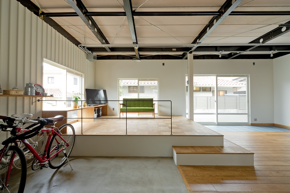 Imagen de salón abierto industrial sin chimenea con paredes blancas y suelo de madera en tonos medios